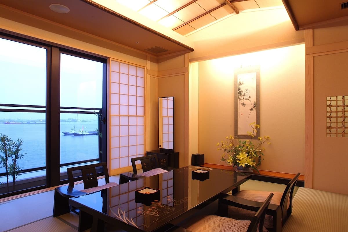 A traditional Japanese-style room with tatami flooring, a low table, and a view of the sea.