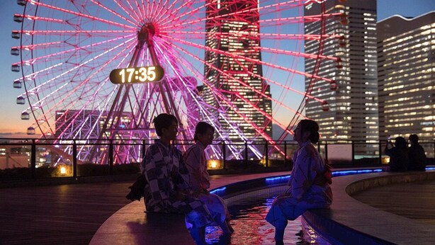 A Ferris wheel with a time display of 17:35, surrounded by modern buildings and a water feature. - Yokohama Minamimirai Manyo-Club (Yokohama)