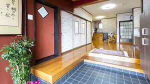 A traditional Japanese interior with sliding doors, a wooden reception desk, and a tiled floor. - Yoshikou (Takahama)