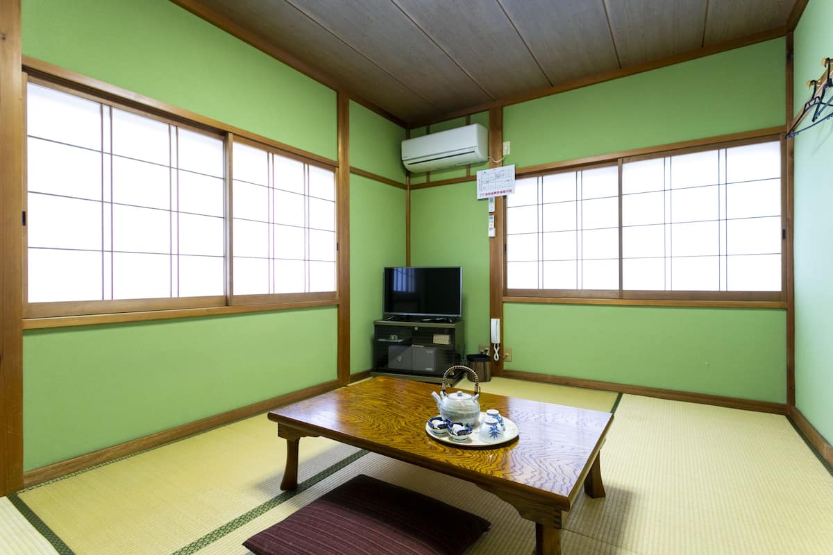 Una habitación de tatami con una mesa baja, un televisor y un tradicional juego de té japonés.