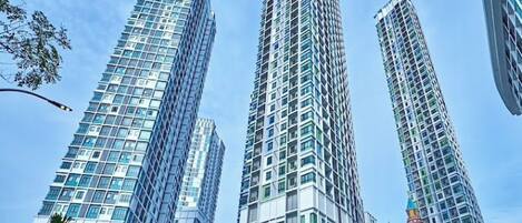 Stunning high-rise building with a sleek glass facade and lush green surroundings.