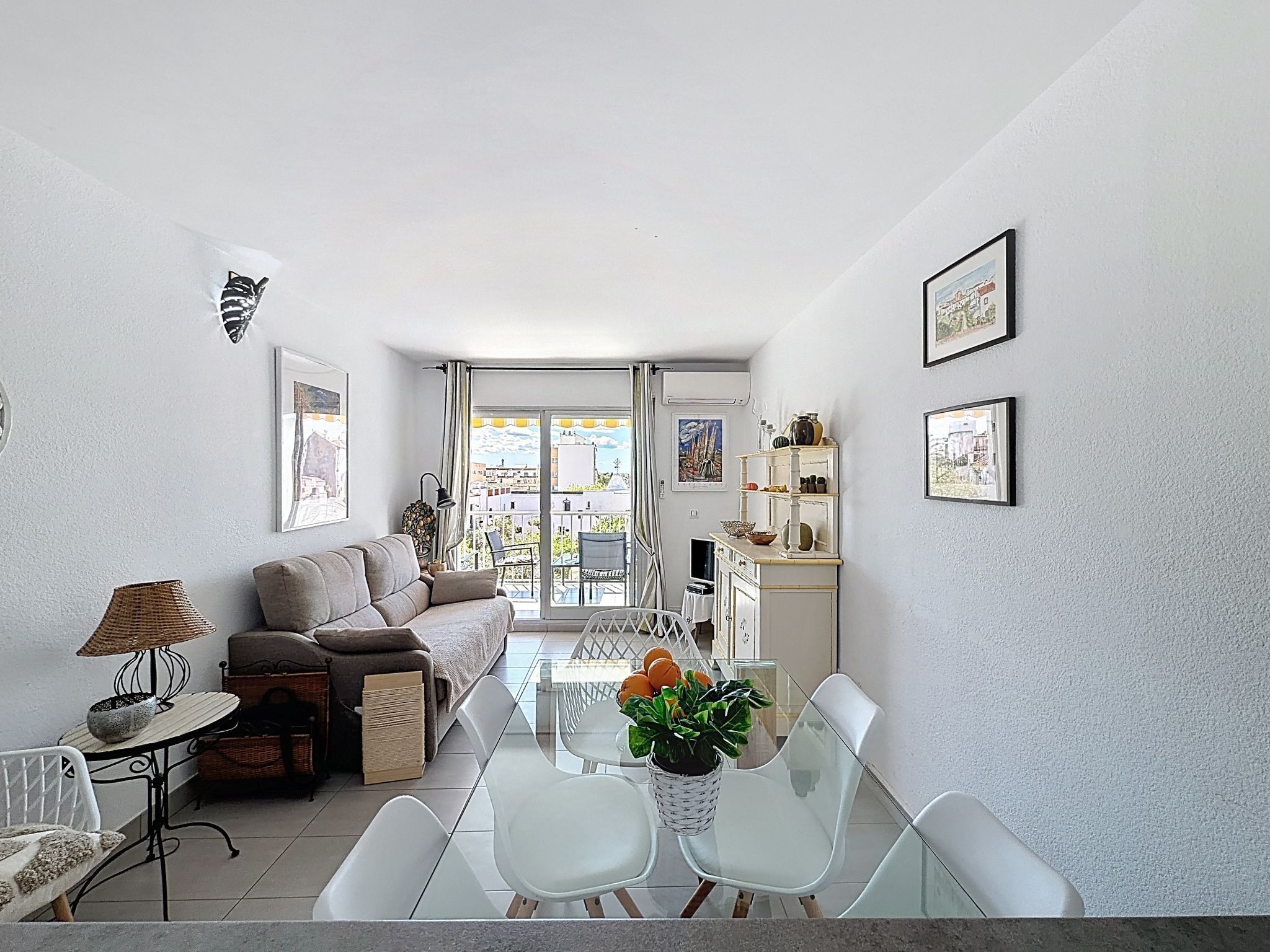 Een moderne woonkamer met een bank, eettafel, stoelen en een balkon met uitzicht.
