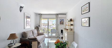 Een moderne woonkamer met een bank, eettafel, stoelen en een balkon met uitzicht.