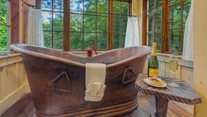 Eine Badewanne mit Handtuch, einer Champagnerflasche und einem Weinglas auf einem Holztisch.