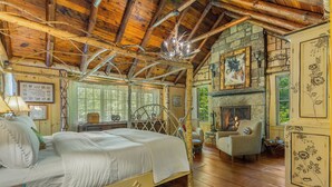 Eine rustikale Holzhütte mit einem großen Bett, einem Kamin und einer Steinwand.