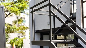 Eine moderne Außenstiege mit Metallgeländern, umgeben von Kübelpflanzen und einem Holzboden.