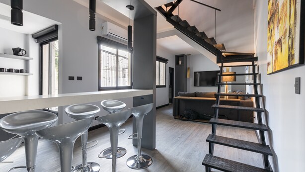 Eine moderne Küche mit Barhocker, einer Treppe und einem großen Fenster.