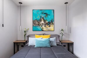 Ein modernes Schlafzimmer mit einem großen Bett, zwei Nachttischen und einem Bild an der Wand.