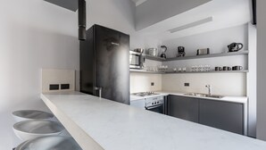 Eine moderne Küche mit einem schwarzen Kühlschrank, weißen Arbeitsplatten und einem eingebauten Backofen.