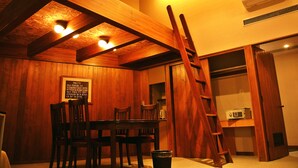 A room with wooden beams, a table with chairs, a ladder, and a microwave in a cabinet. - Sora no Mori Hotel Hanagori (Kami)