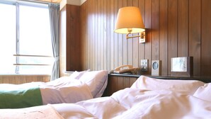 A hotel room with two beds, a lamp, a phone, and a window with curtains. - Sora no Mori Hotel Hanagori (Kami)