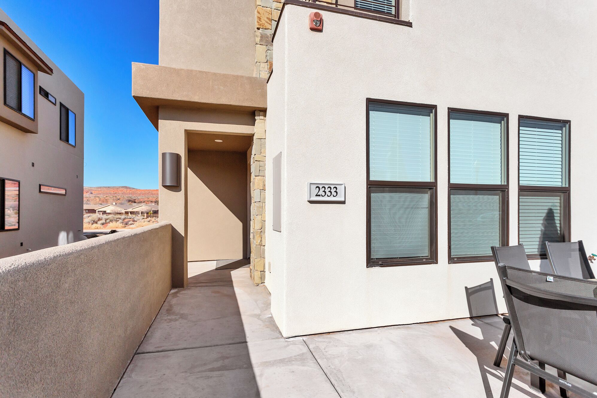 A building with a number 2333 sign, a covered outdoor seating area, and a view of a desert landscape.