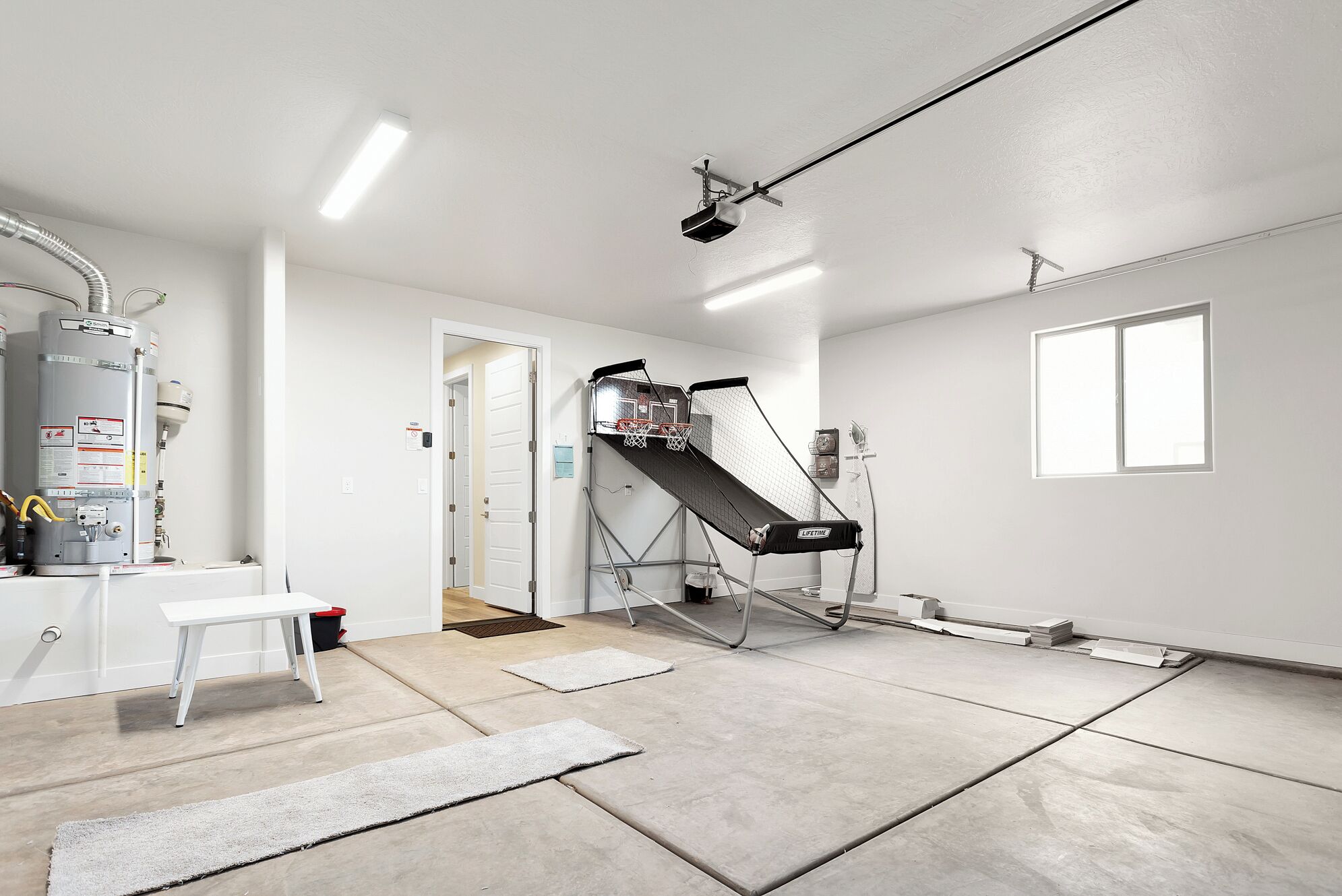 Una habitación con pared blanca, ventana, banca blanca y calentador de agua.