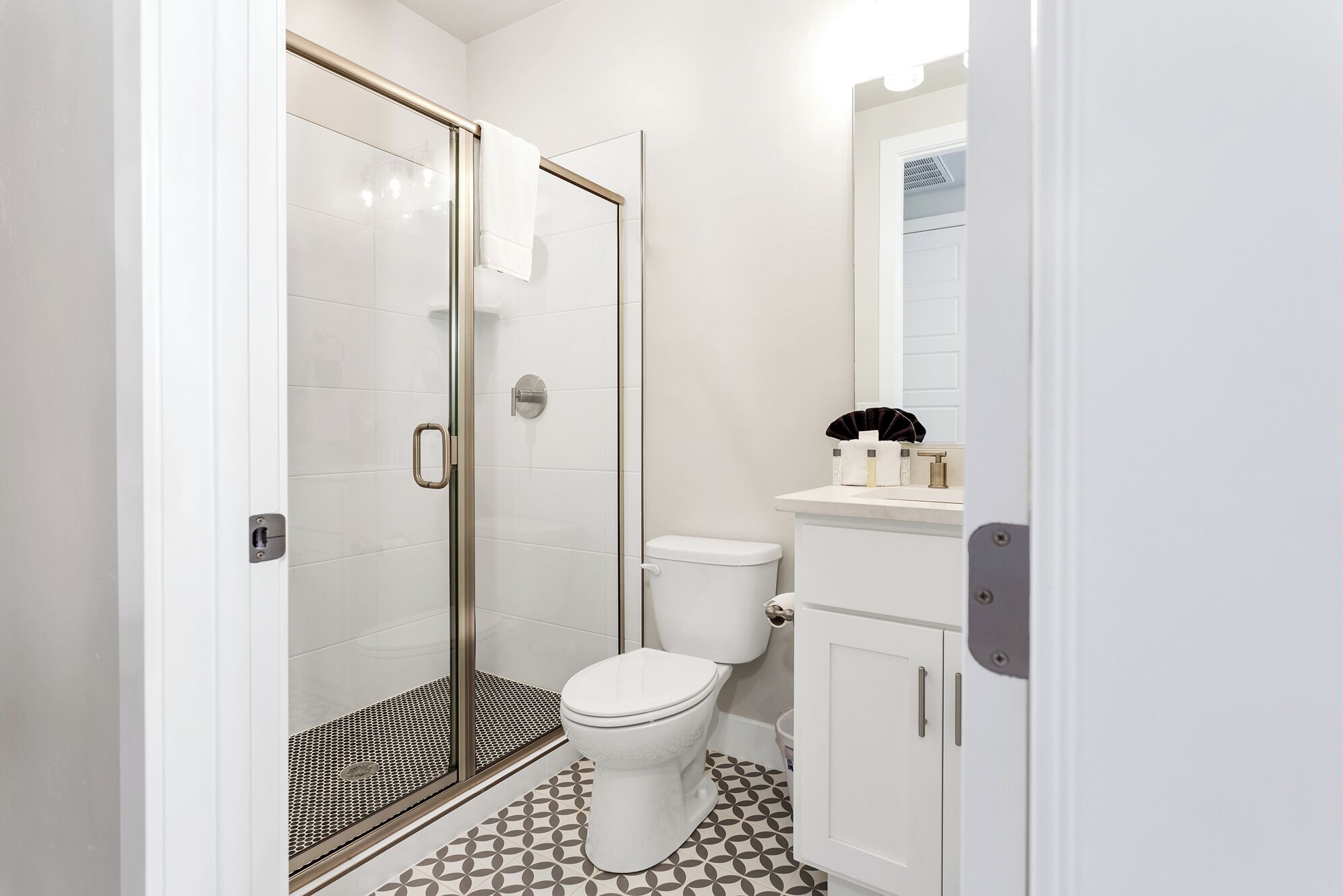 Un baño con ducha de vidrio, inodoro y lavabo con espejo superior.