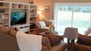 Een woonkamer met een grote flatscreen televisie, een bank, een salontafel en een boekenkast.