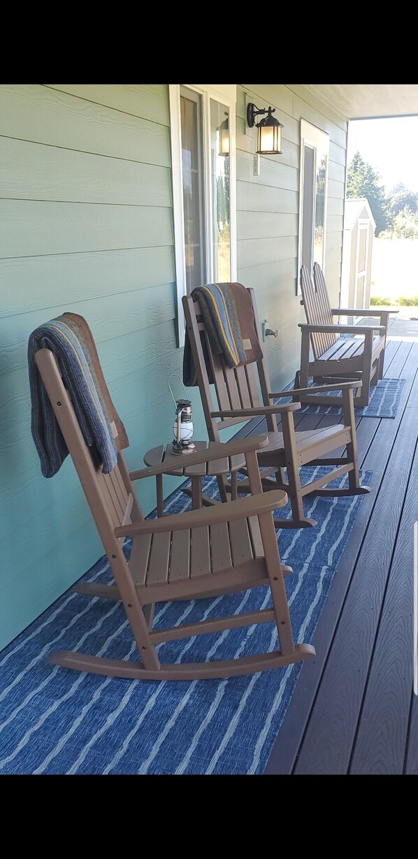A porch with three rocking chairs, a small table, and a lantern.