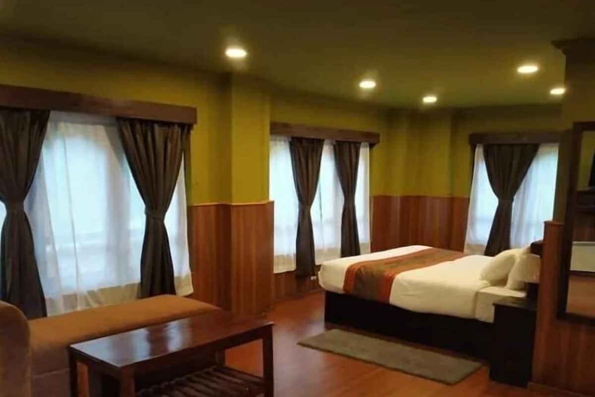 A hotel room with a bed, a small table, and curtains.
