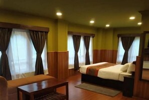 Habitació d'hotel amb llit, una taula petita i cortines.