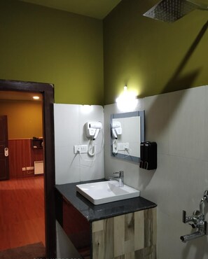 Un bany amb un lavabo blanc, un mirall i dos assecagats de mans.