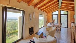 A spacious living area with a fireplace, large windows offering a view of the countryside, and wooden ceiling beams. - Wonderful private villa with pool, A/C, WIFI, balcony and panoramic view, close to Greve In Chia... (Tavarnelle Val Di Pesa)