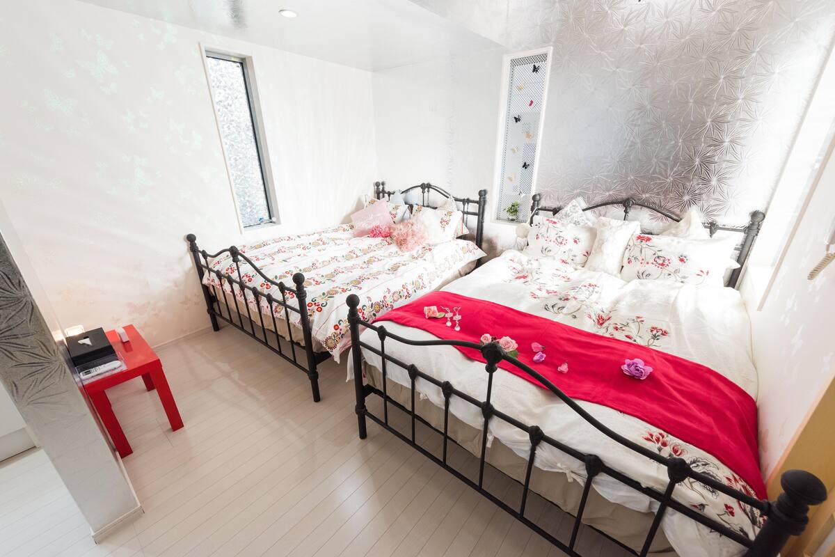 Une chambre avec deux lits, une chaise rouge et une fenêtre.
