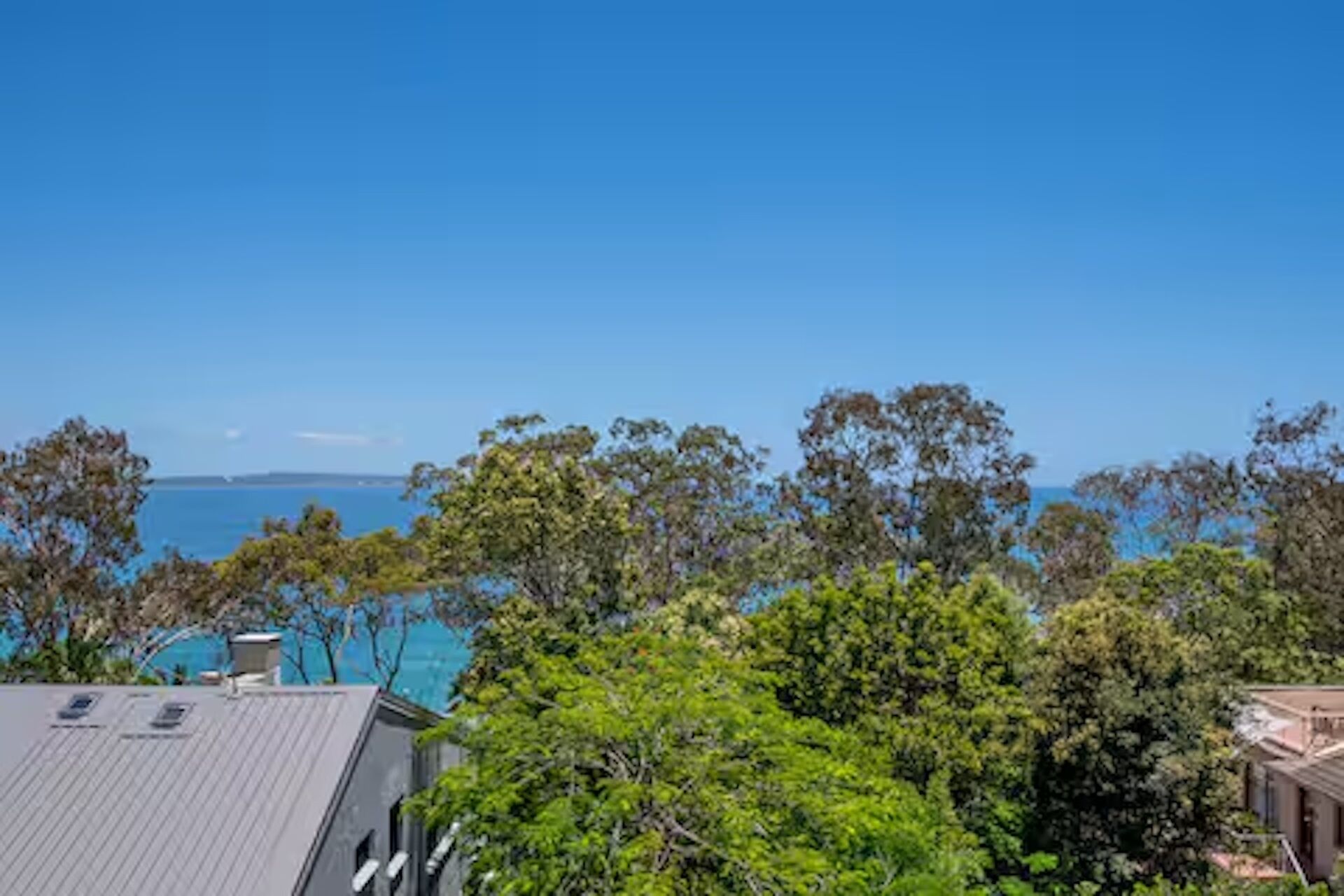 A residential area with a clear view of the ocean and a distant landmass.
