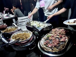 Una mesa de comedor con diversos platos, como fideos, carne a la parrilla y verduras.