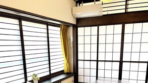 A traditional Japanese room with tatami flooring, a low table, sliding shoji doors, and a hanging paper lantern. - Mitsuba House (Annaka)