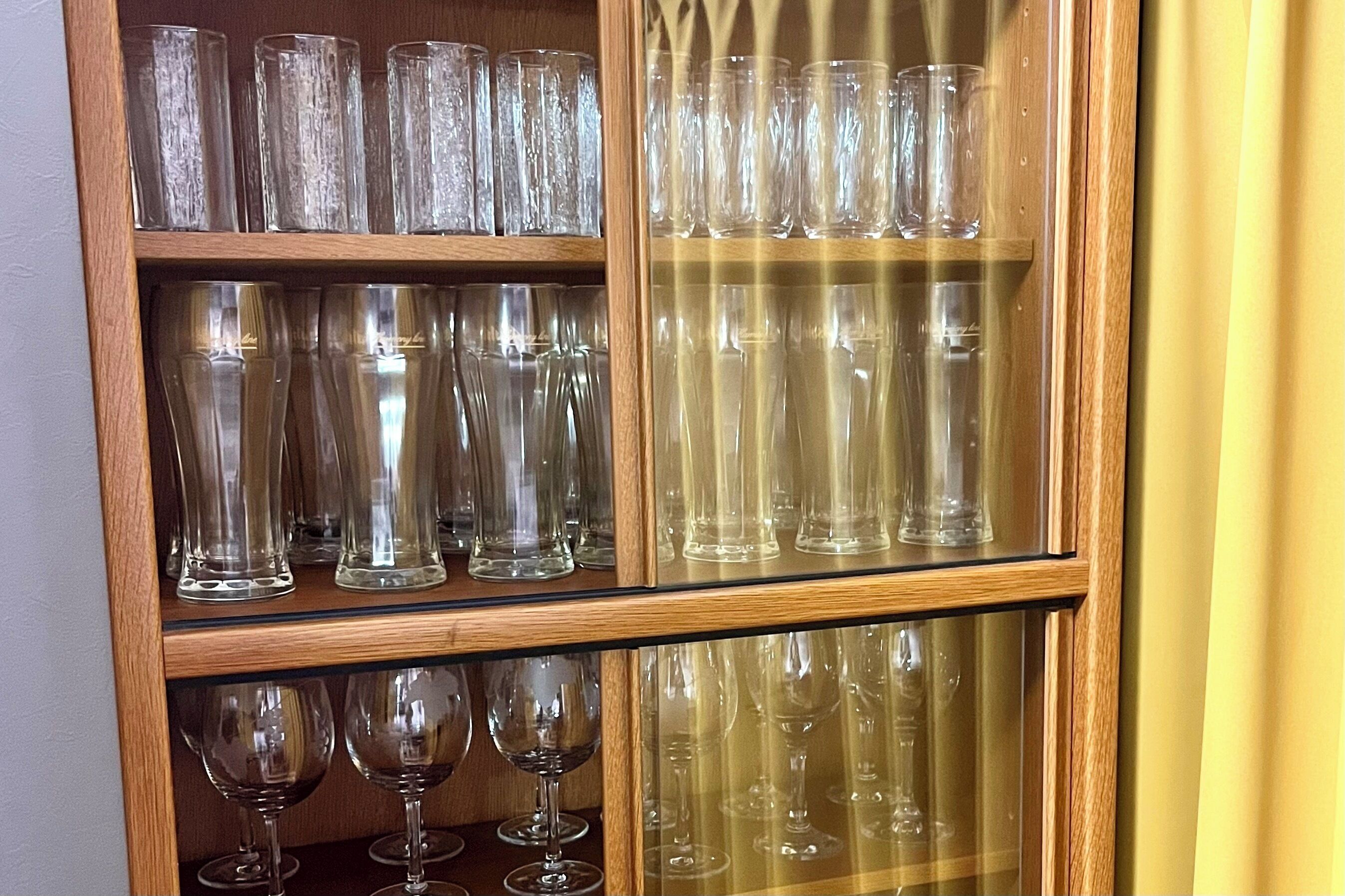 A wooden cabinet with multiple shelves containing various clear glassware items.