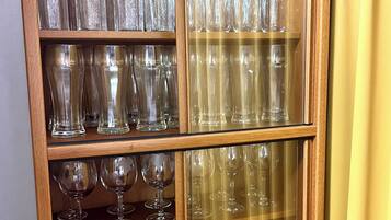 A wooden cabinet with multiple shelves containing various clear glassware items.