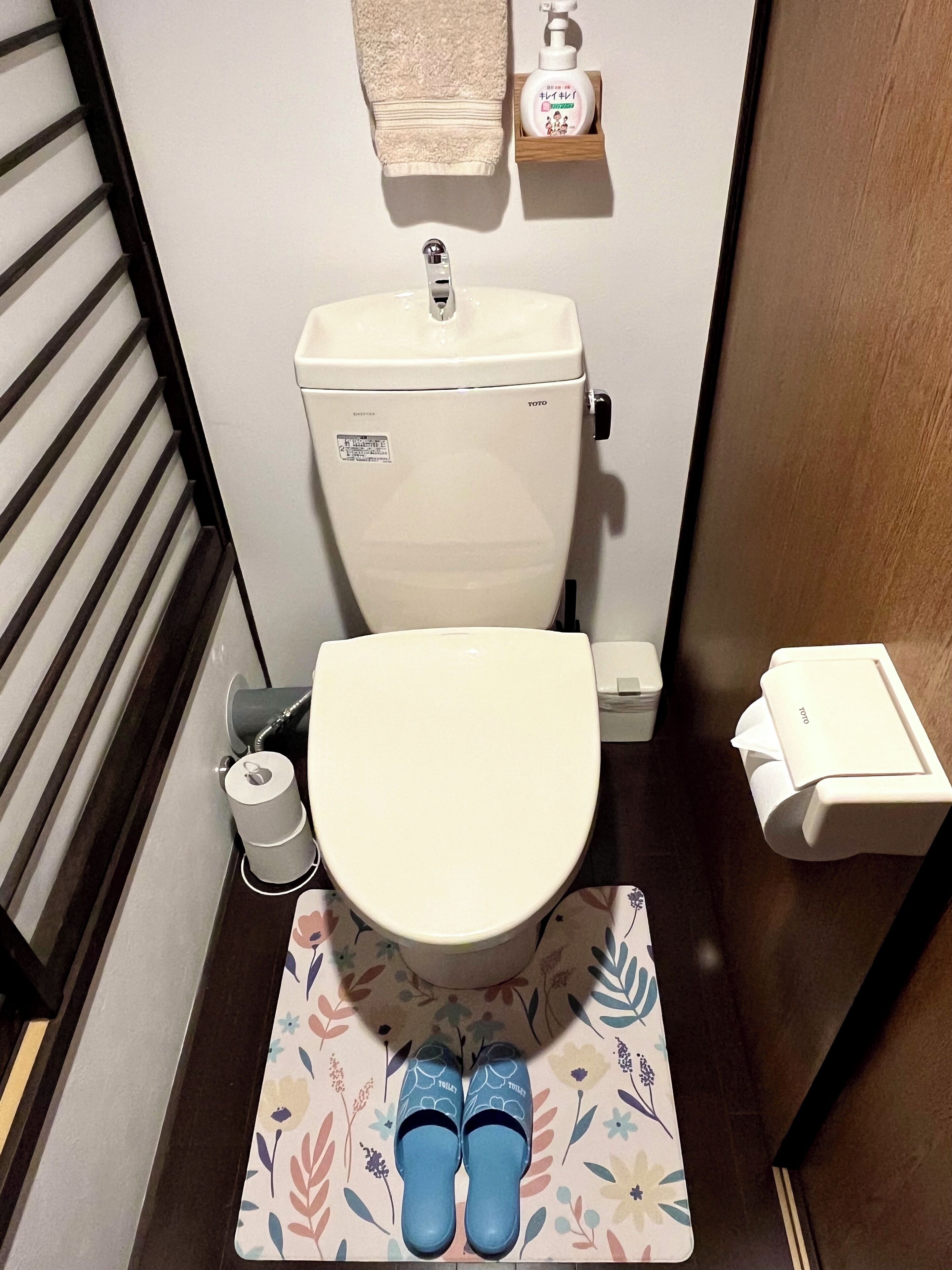 Ein kleines Badezimmer mit Toilette, Toilettenpapierhalter und Handtrockner.