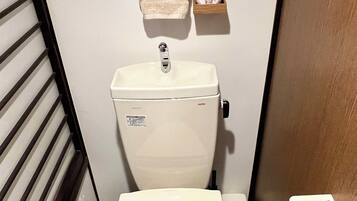 Ein kleines Badezimmer mit Toilette, Toilettenpapierhalter und Handtrockner.