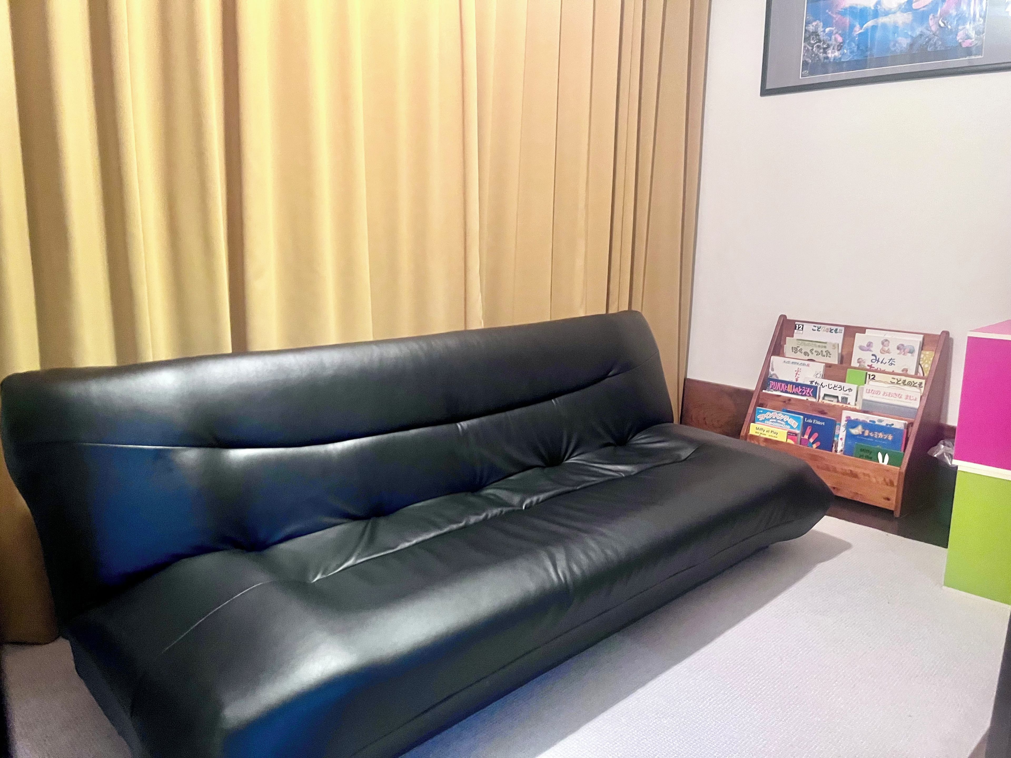 A black leather sofa in a room with a wooden headboard and a framed picture on the wall.