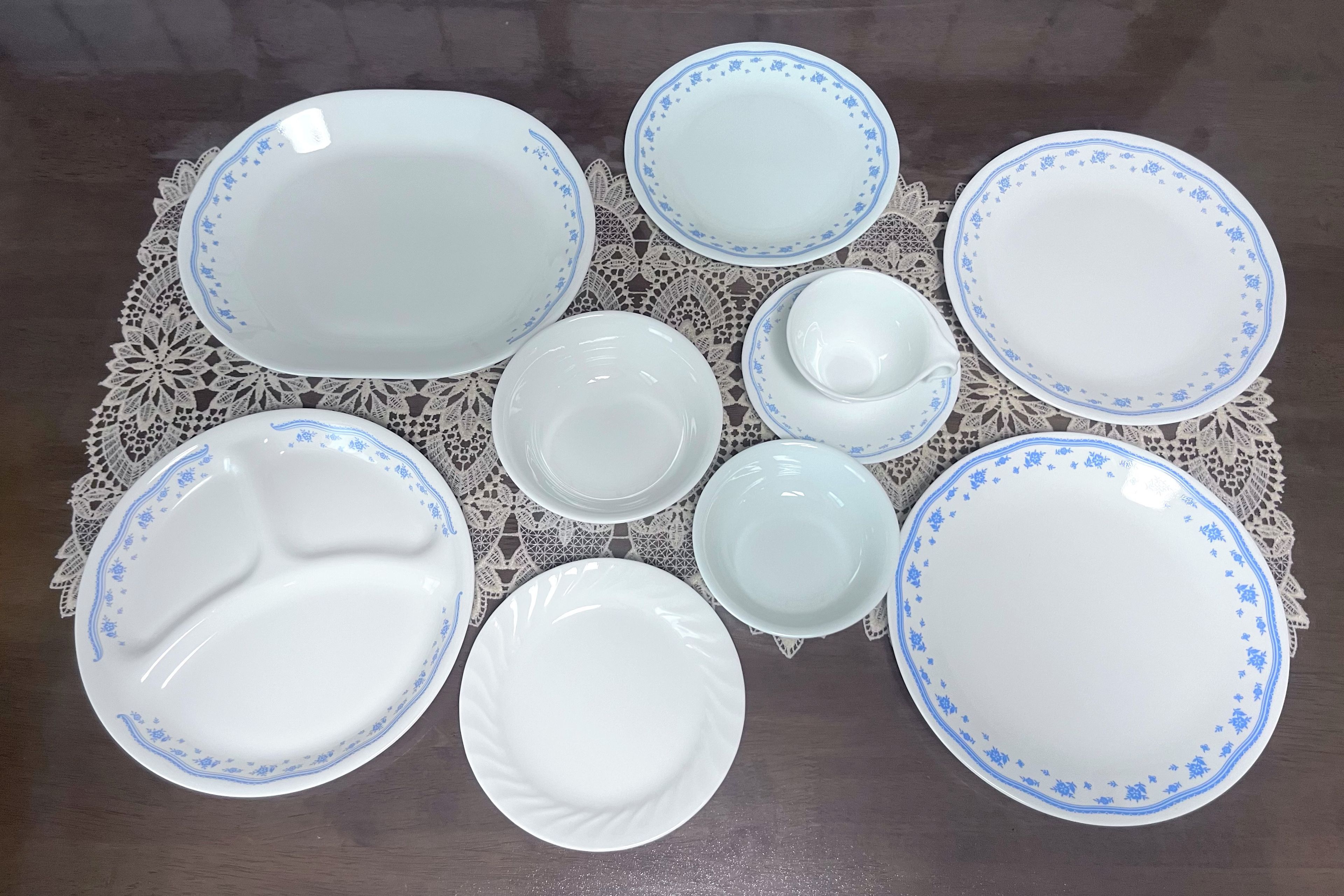 A collection of white plates with blue floral patterns arranged on a lace tablecloth.