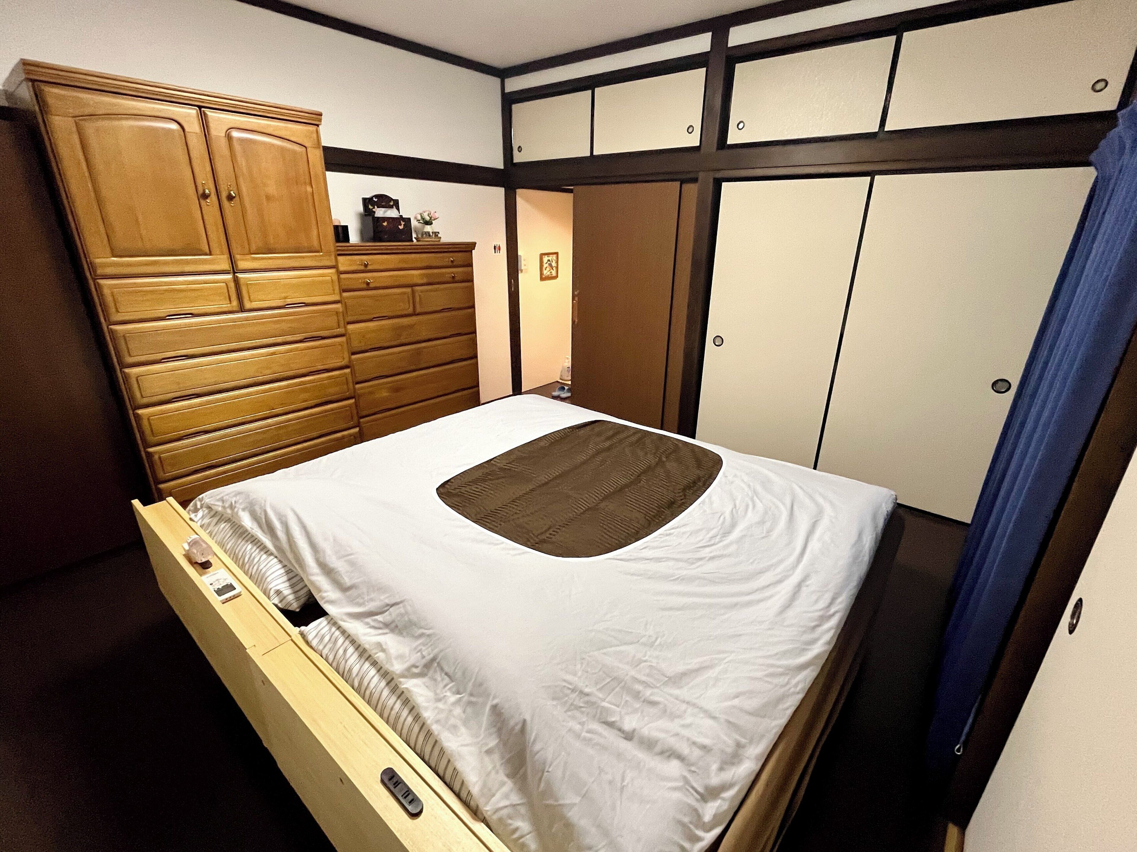 A single bed with a wooden headboard, a dresser, and a wardrobe with a sliding door.