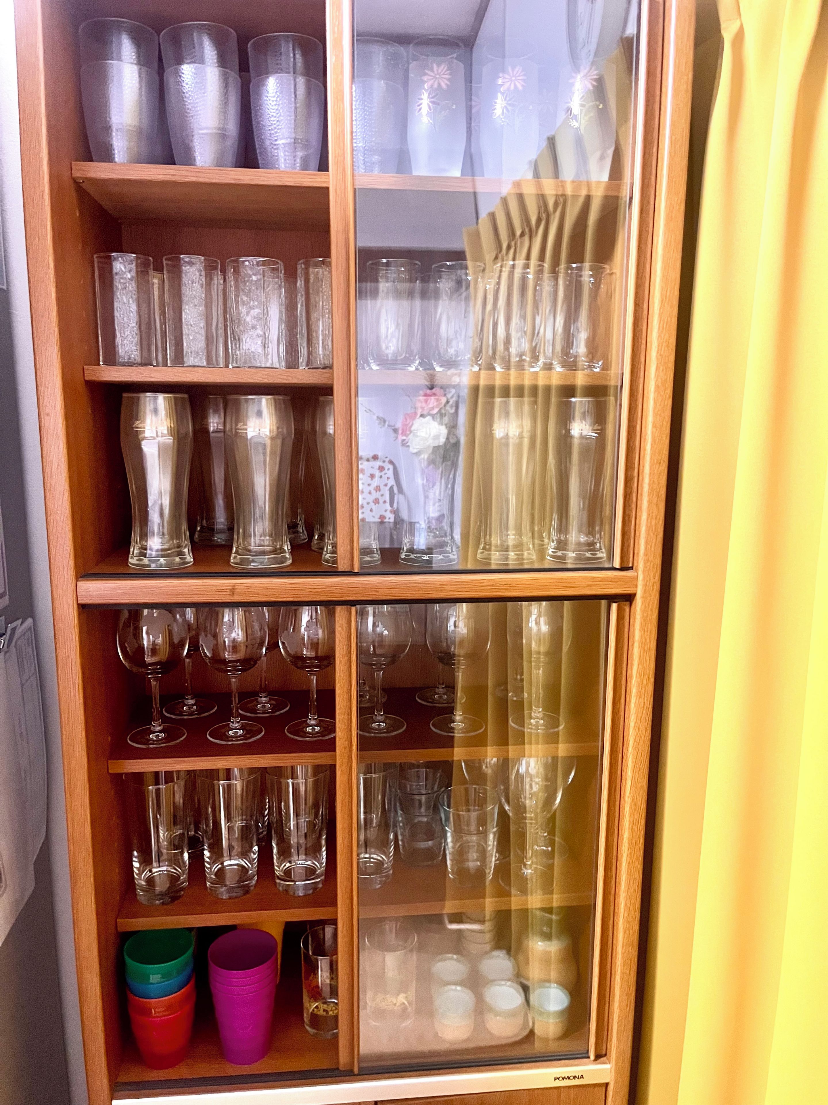 Un expositor de vidrio con diferentes vasos, incluyendo copas de vino y vasos sencillos.