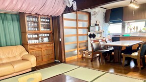 A traditional Japanese-style living room with tatami flooring, a low wooden table, and a sofa.
