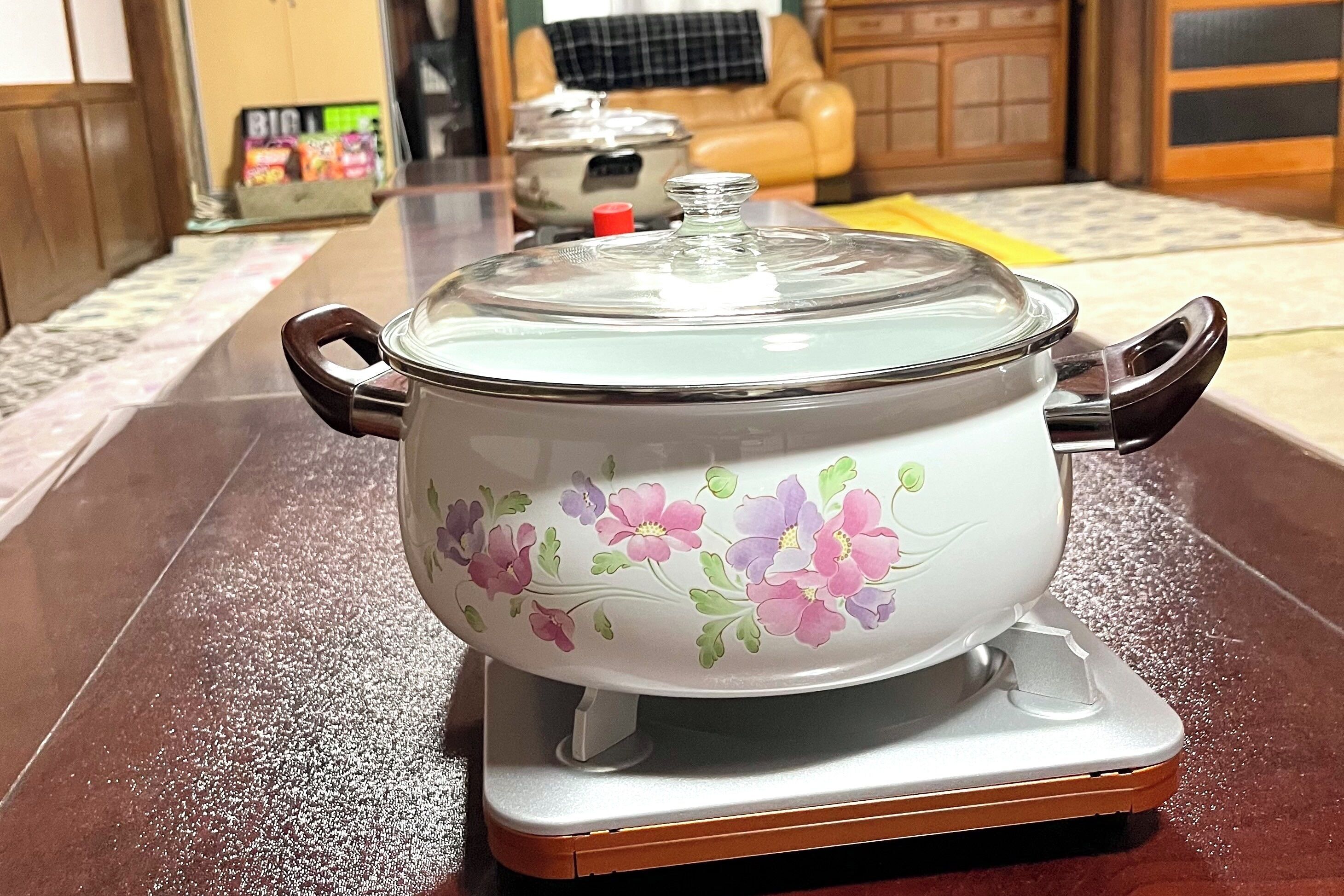 A kitchen with a stove, a pot on the stove, and a chair in the background.
