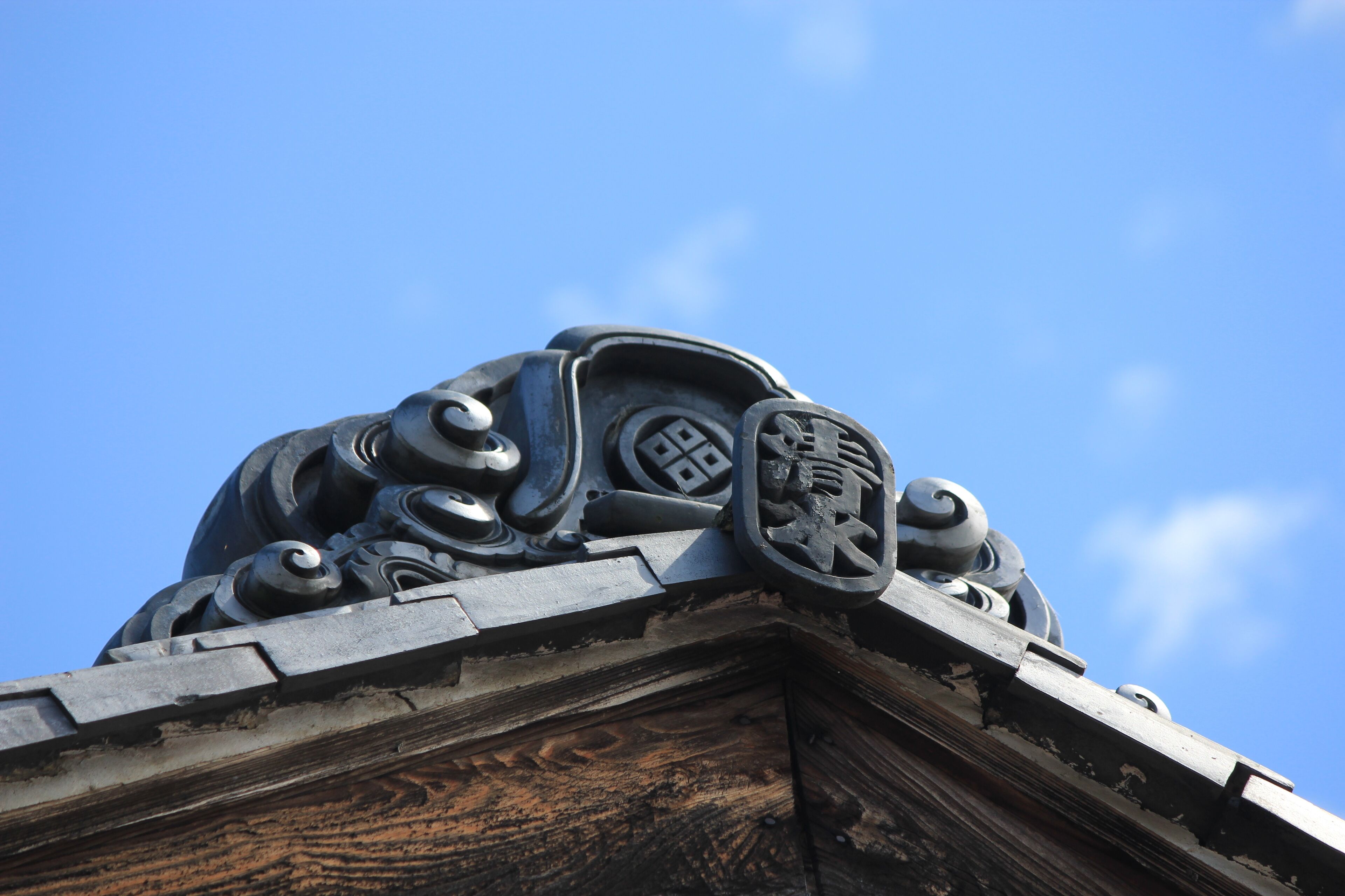 A detailed architectural feature with ornamental designs and inscriptions on a building's corner.