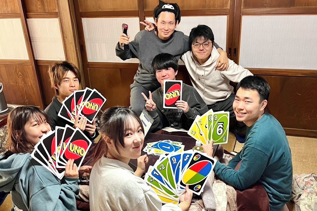 Un grupo de personas sentadas alrededor de una mesa jugando a UNO.