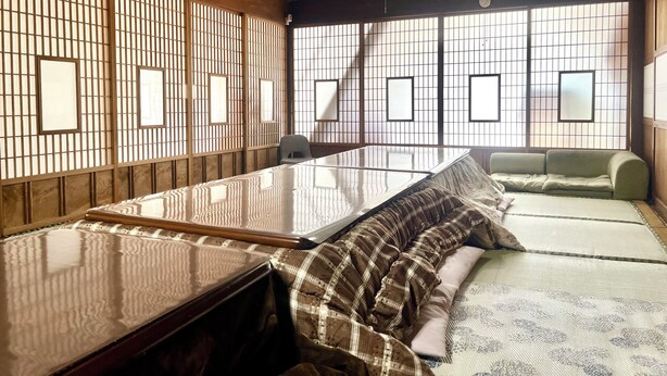 Quarto em estilo japonês tradicional, com tatames, uma mesa baixa e portas corrediças com desenhos em grade.