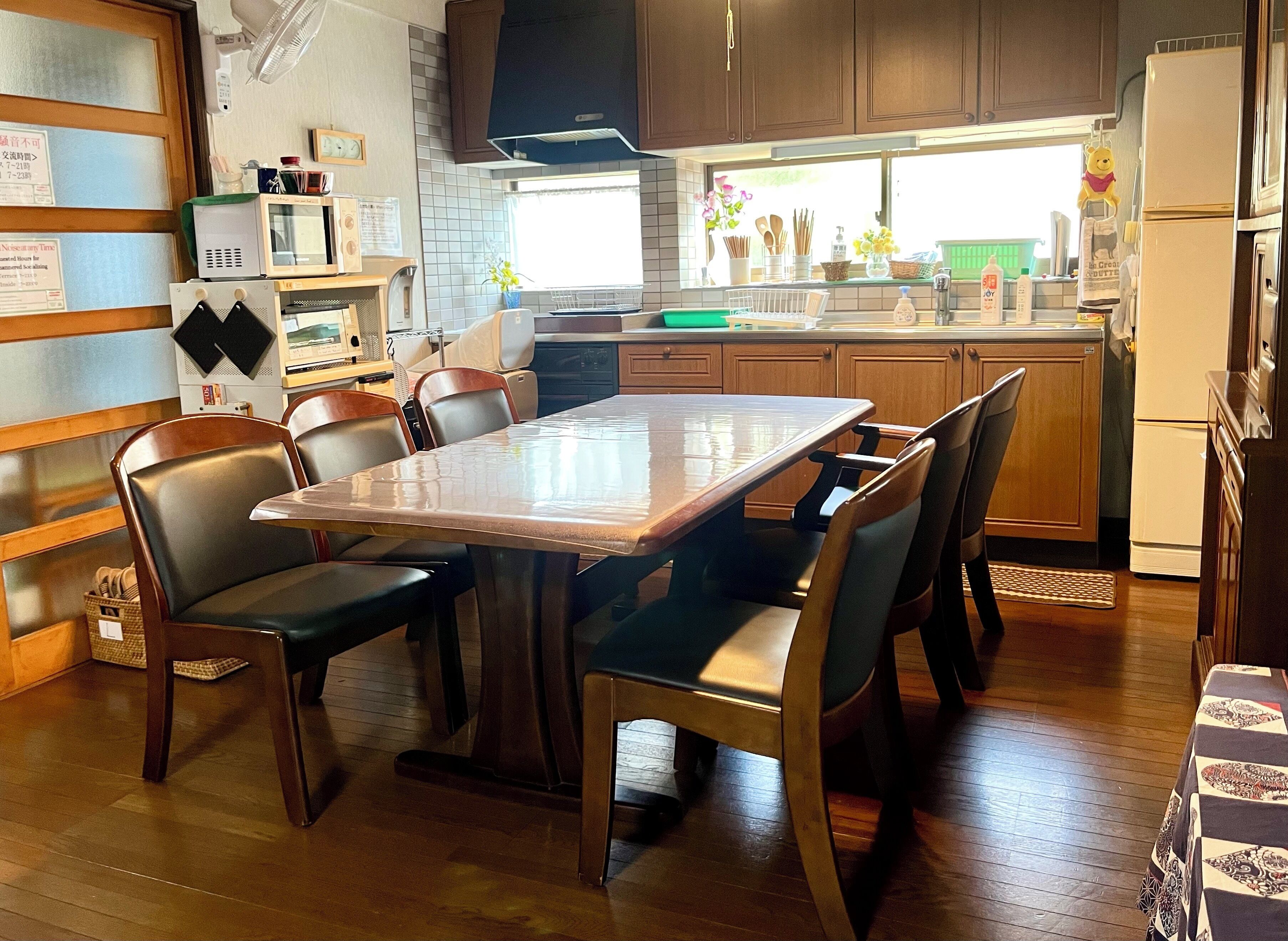 A compact kitchen with a dining table, chairs, wooden cabinets, a microwave, and a refrigerator.