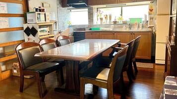 A compact kitchen with a dining table, chairs, wooden cabinets, a microwave, and a refrigerator.