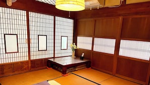 Um quarto tradicional japonês com tatames, uma mesa de madeira baixa e biombos de papel.