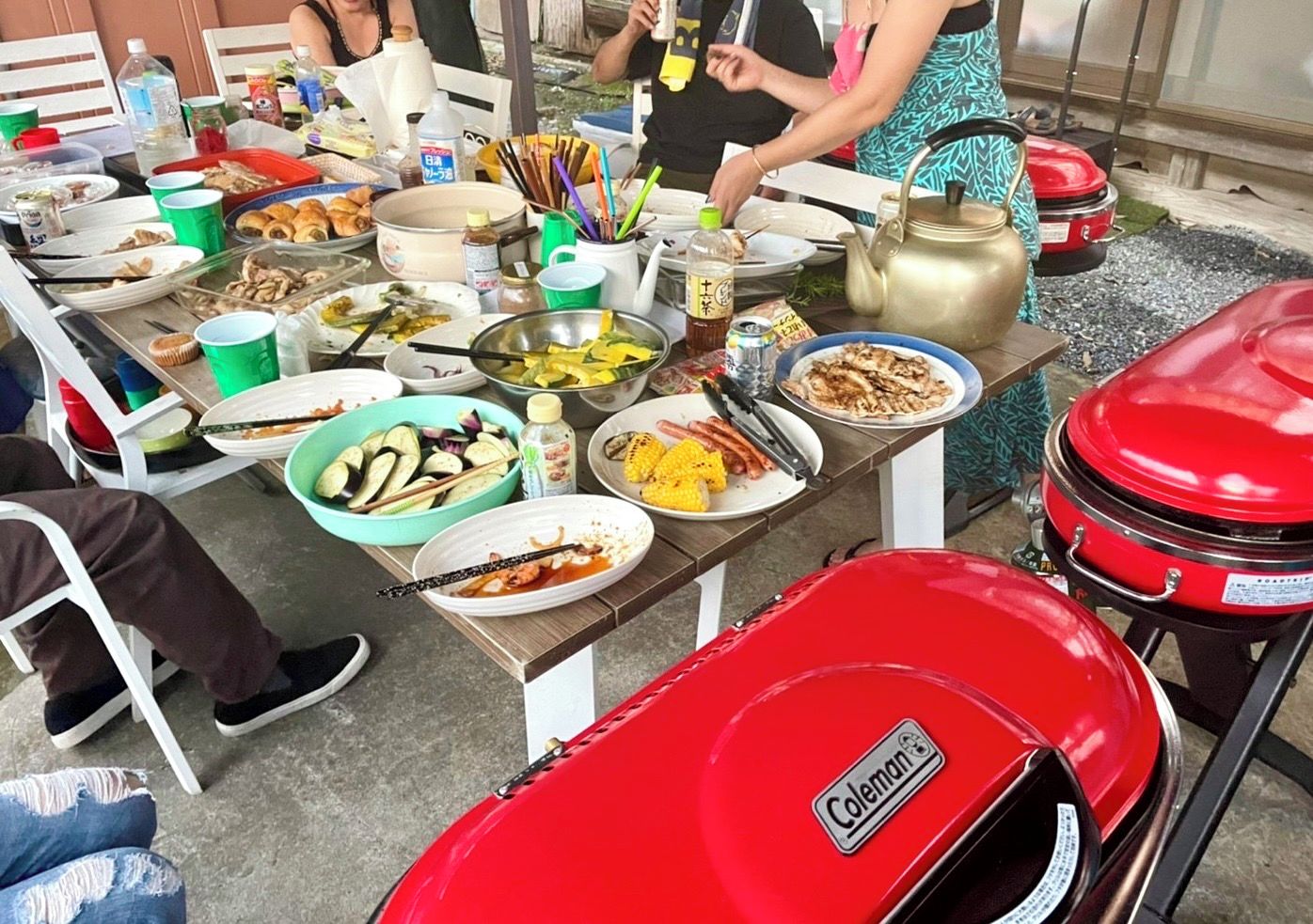 A communal dining table with various dishes and a Coleman grill.