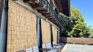 A building with a wooden facade and a covered outdoor seating area with white chairs.