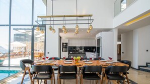 A modern dining area with a large table, black chairs, and hanging light fixtures. - Villa Unlimited Duo, luxury 6 bedroom villa (Antalya)