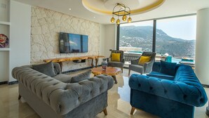 A modern living room with a stone wall, a flat-screen TV, a wooden coffee table, and a sofa. - Villa Unlimited Duo, luxury 6 bedroom villa (Antalya)