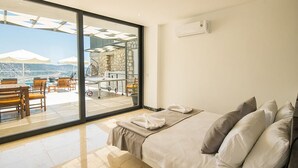 A bedroom with a large sliding glass door leading to an outdoor terrace with seating and umbrellas. - Villa Unlimited Duo, luxury 6 bedroom villa (Antalya)