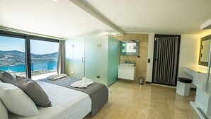 A modern hotel room with a large bed, a bathroom, and a view of the sea. - Villa Unlimited Duo, luxury 6 bedroom villa (Antalya)